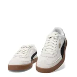 Championes urbanos Puma modelo Club II Era Suede, confeccionados en gamuza color gris claro con la icónica franja lateral en negro y suela de goma color caramelo.