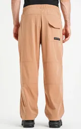 Pantalón de corte recto confeccionado en microfibra liviana y ligeramente elastizada. Presenta cintura elástica con cordón de ajuste, bolsillos laterales y un bolsillo trasero con tapa y velcro. Incluye recortes horizontales en las piernas y un pequeño logo bordado en el muslo.
