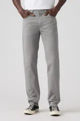 Pantalón de corte slim fit confeccionado en sarga de algodón con elastano, color gris. Presenta diseño clásico de cinco bolsillos, cierre de botón y cremallera, y costuras reforzadas.