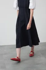 Vestido midi sin mangas de color azul oscuro, con escote cuadrado y silueta evasé. Presenta costuras a contratono en color blanco que recorren verticalmente el diseño, aportando estructura y un detalle gráfico. Confeccionado en tejido con cuerpo y caída firme.
