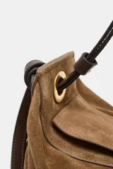 Bolso de mano formato alargado confeccionado en piel, con doble asa, una de mano y otra de hombro, con detalle de nudos y ojales metálicos. Cuenta con cierre mediante solapa y cremallera, y bolsillo interior con cremallera.