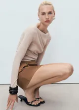 Camiseta entallada de manga larga en color beige, con elegante cuello barco y diseño liso.