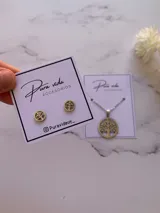 Set de joyería compuesto por aros tipo abridores y collar con dije circular, ambos con diseño calado del Árbol de la Vida en acero quirúrgico.