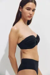 Top de bikini balconette negro con copas acolchadas, aros, varillas laterales y detalle girado en el centro. Incluye tirantes ajustables y extraíbles.