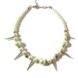 Collar de perlas blancas de diferentes tamaños, con detalles de hematita plateada y púas metálicas.