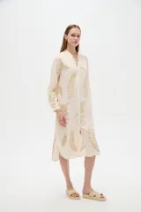 Vestido midi holgado de viscosa color beige, con mangas largas, cuello mao, cierre frontal con botones y detalle de bordado con lurex con diseño de hojas doradas.