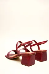 Sandalia de cuero vacuno color negro con textura de cocodrilo, taco cuadrado de 4 cm, punta cuadrada y dos tiras finas, una en el empeine y otra con hebilla en el tobillo.