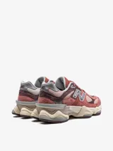 Championes New Balance modelo 9060, con diseño inspirado en la estética tecnológica del año 2000. Presentan una combinación de tonos rojizos y rosados con detalles en gris y beige. Cuentan con amortiguación ABZORB y SBS, y una mediasuela ergonómica con diseño robusto.