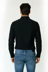 Camisa de algodón color negro, de corte holgado, con cuello camisero y cierre frontal de botones.