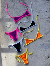Conjunto de bikini triangular con tiras finas, disponible en color negro con borde blanco, naranja con borde amarillo y violeta con borde fucsia.