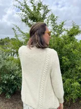 Cardigan tejido a mano color crudo, con solapa en el escote y punto delicado.