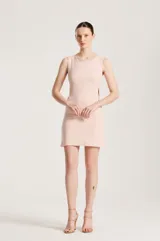 Vestido corto sin mangas de color rosado, con escote redondo al frente, corte recto y detalles de aberturas laterales con tachas metálicas.