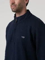 Buzo de tejido de punto color azul marino jaspeado, con cuello alto y cierre frontal parcial. Presenta un pequeño logo bordado en el pecho.