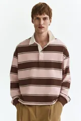 Remera tipo polo de manga larga con diseño a rayas horizontales en tonos rosado y marrón, con cuello blanco de sarga y cierre frontal con botones ocultos.
