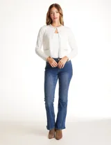 Chaqueta tejida blanca de la marca Rio & Rian, con cuello a la base bordado con perlas y canutillos. Cuenta con broche de enganche interno, bolsillos simulados en la delantera con aplique de brillos, y vivo delantero y puños en tejido lurex.