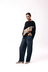 Sweater de punto con diseño de bloques de color en diagonal, combinando negro, beige y una franja central con textura metalizada. Presenta cuello redondo, mangas largas con puños en contraste y un corte holgado.