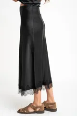 Falda midi negra de acabado satinado, corte al bies, con detalle de encaje en el ruedo.