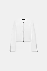 Chaqueta de punto liso color blanco, con cuello redondo, manga larga acabada con cremalleras en los puños y cierre frontal con cremallera.