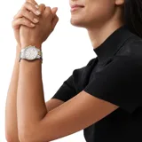 Reloj cronógrafo Michael Kors modelo Ritz con caja de 37 mm, esfera blanca con índices de cristal y bisel decorado con cristales. Presenta una pulsera de eslabones en acero inoxidable bicolor, dorado y plateado.