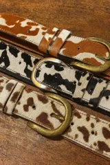 Cinto de cuero vacuno con pelo natural, con diseño de manchas tipo animal print. Cuenta con hebilla metálica y costuras reforzadas.