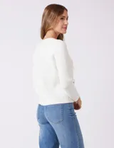 Cardigan de punto color fucsia, con escote a la base, cierre frontal con botones metálicos dorados y terminaciones desflecadas. Presenta bolsillos simulados en la parte delantera y mangas largas.