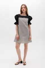 Vestido corto con cuerpo a rayas verticales en tonos beige y blanco, mangas cortas abullonadas y canesú superior en color negro.