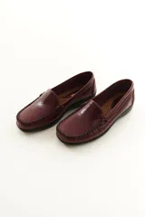 Mocasines de cuero vacuno color beige con acabado mate, costuras visibles artesanales en el empeine y suela de perfil bajo.