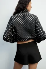 Falda pantalón de tiro medio color negro, con detalle de abertura en el delantero y cierre lateral con cremallera oculta.