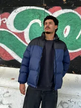 Campera puffer azul con canesú negro y cierre frontal.