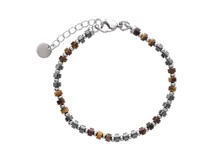 Pulsera compuesta por una alternancia de cuentas de piedra natural en tonos tierra, cuentas metálicas esféricas y cuentas cilíndricas de hematita. Incluye cadena de alargue con dije circular liso y cierre de mosquetón.