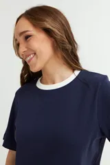 Remera blanca de algodón con cuello redondo y mangas cortas. El cuello es de color azul marino en contraste.