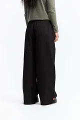 Pantalón de vestir negro de corte wide leg, con cintura elástica ajustable mediante cordón, pliegues frontales y diseño holgado.