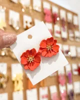 Aros tipo caravana en forma de flor color rojo con centro dorado y estambres detallados.