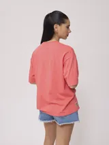 Remera color amarillo pastel con estampado de palmeras, flores de hibisco y texto 'California Ride the Tide Rusty Tribe'.