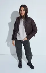 Campera puffer de nylon color marrón oscuro, con cuello alto, cierre frontal y puños elásticos. Diseño acolchado de volumen ligero.