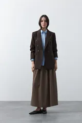 Camisa blanca de manga larga con detalles bordados en contraste a lo largo de la botonadura, el cuello y los puños. Presenta una silueta relajada y un diseño clásico con un toque artesanal.