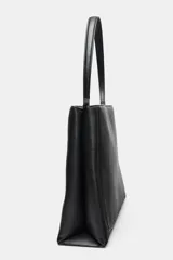 Bolso de hombro formato saca, color negro, con detalle de pespuntes en el cuerpo, asa de hombro y cierre mediante botón imantado.