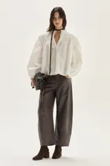 Blusa blanca de algodón con escote alto, detalles de smock y tablitas en el canesú y hombros, y mangas largas abullonadas con puños fruncidos.