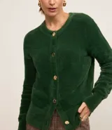 Cardigan de punto verde oscuro, con textura afelpada y cuello redondo. Cierre frontal con botones dorados y mangas largas con puños largos.