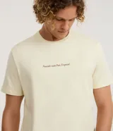 Remera de algodón color amarillo claro, de corte cómodo y manga corta, con cuello redondo y estampa pequeña con la frase "Nascido num País Tropical" en el pecho.