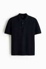 Remera polo de manga corta en punto texturizado negro, con cuello y tapeta de tres botones. Remate acanalado en puños y bajo, con un corte estándar.