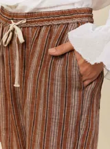 Pantalón babucha de lino a rayas verticales marrones y blancas, con cinturilla elástica con lazo para anudar y tres bolsillos funcionales.
