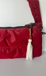 Llavero dorado con flecos de cuero sintético y gancho metálico.