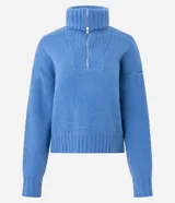 Suéter de punto azul con cuello alto y cierre frontal de cremallera metálica. Presenta textura de líneas verticales, corte regular, mangas largas y terminaciones acanaladas.