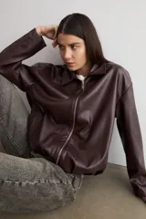 Chaqueta bomber de eco cuero color bordó, con cierre frontal plateado, cuello clásico y mangas largas con diseño holgado.