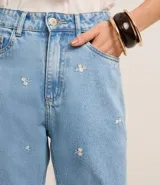 Pantalón recto cropped de jeans celeste con bordados de flores blancas.