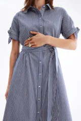 Vestido midi camisero con estampado de rayas verticales en tonos azul y blanco, cuello camisero, botonadura frontal y mangas cortas. Incluye un cinturón para anudar en la cintura y falda de corte acampanado.