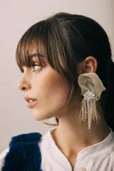 Aros colgantes con diseño de flor en rafia color beige, decorados con una pieza central de strass y flecos de hilo y cristales colgantes.
