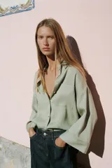 Camisa de corte oversize color marrón, con cuello solapa, mangas anchas por debajo del codo y bolsillo delantero de plastrón. Cierre frontal con botones.