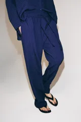Pantalón de tiro medio con diseño de pierna ancha y textura acanalada. Cuenta con cintura elástica ajustable mediante cordones.